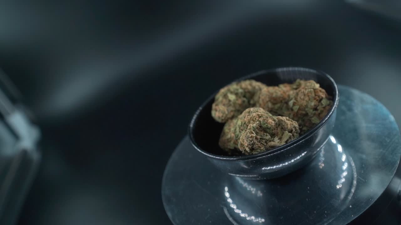 Grayish Green Dried Marijuana Buds Close Up Shot, pile of dried marijuana plants in a shiny bowl, trichomes strains, on a reflecting rotating stand, studio lights, cinematic crane rotating slow motion