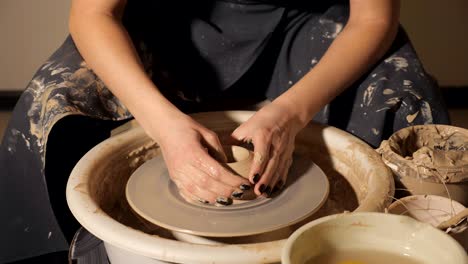 the girl makes a pot of clay on a potter's wheel. hands closeup