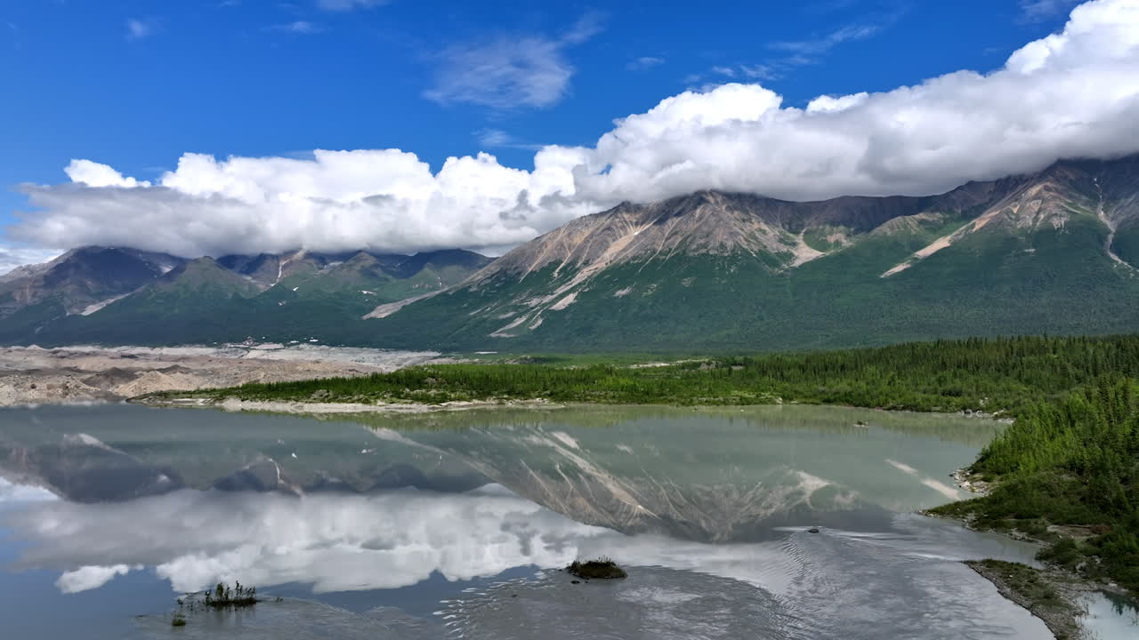 Sorge sul fiume riflettendo le meravigliose montagne con cime coperte di nuvole soffici. Splendida natura dell'Alaska, USA
