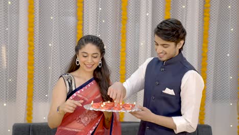 Indian-couple-setting-up-earthen-lamps-on-Diwali