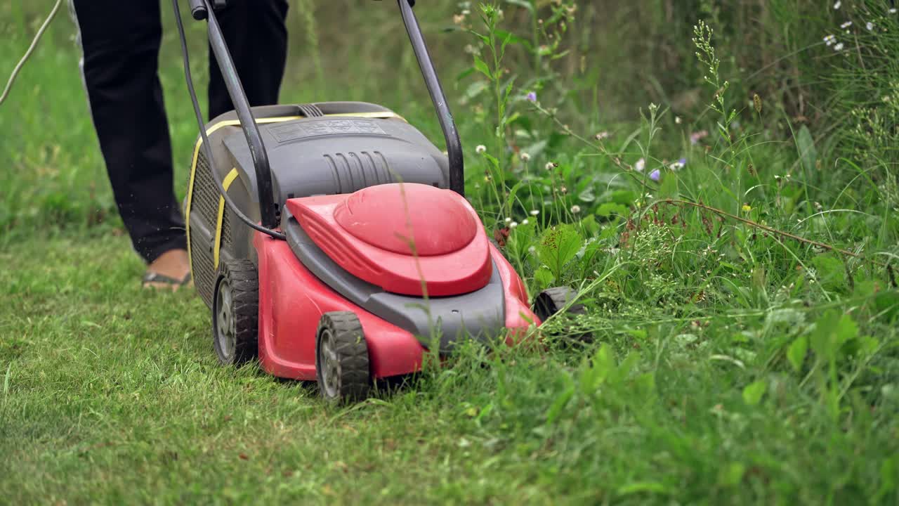 Close-up of mowing the lawn. Female Mowing Lawn in Suburbs.
