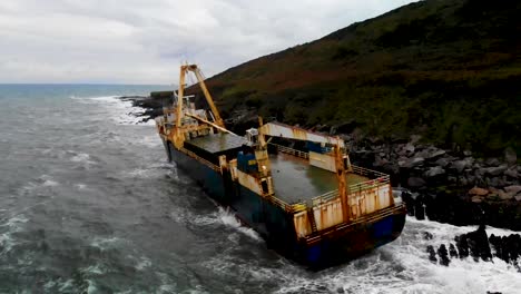 shipwreck in a bay, abandoned ghost ship aerial footage, camera rotated around the back of the ship