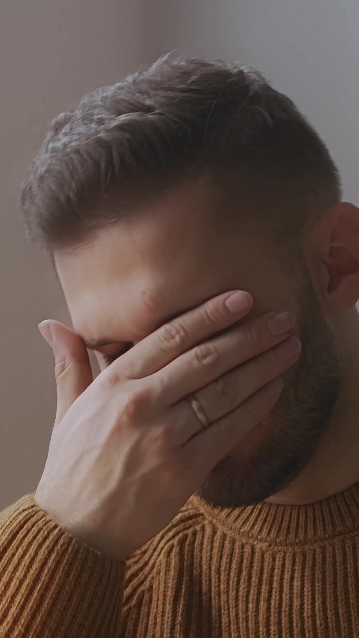 Giovane uomo frustrato che si copre il viso con la mano