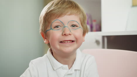 Un-Lindo-Niño-Con-Gafas-Pintadas-Sonríe-Mirando-A-La-Cámara