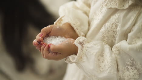 Young-little-girl-holding-fake-Christmas-snow-in-between-her-hands---High-angle-close-up-shot