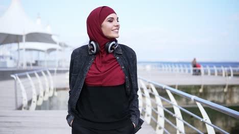 Slow-motion-outdoors-footage-of-a-young-muslim-girl-having-a-walk-near-the-sea-side,-enjoying-her-free-time