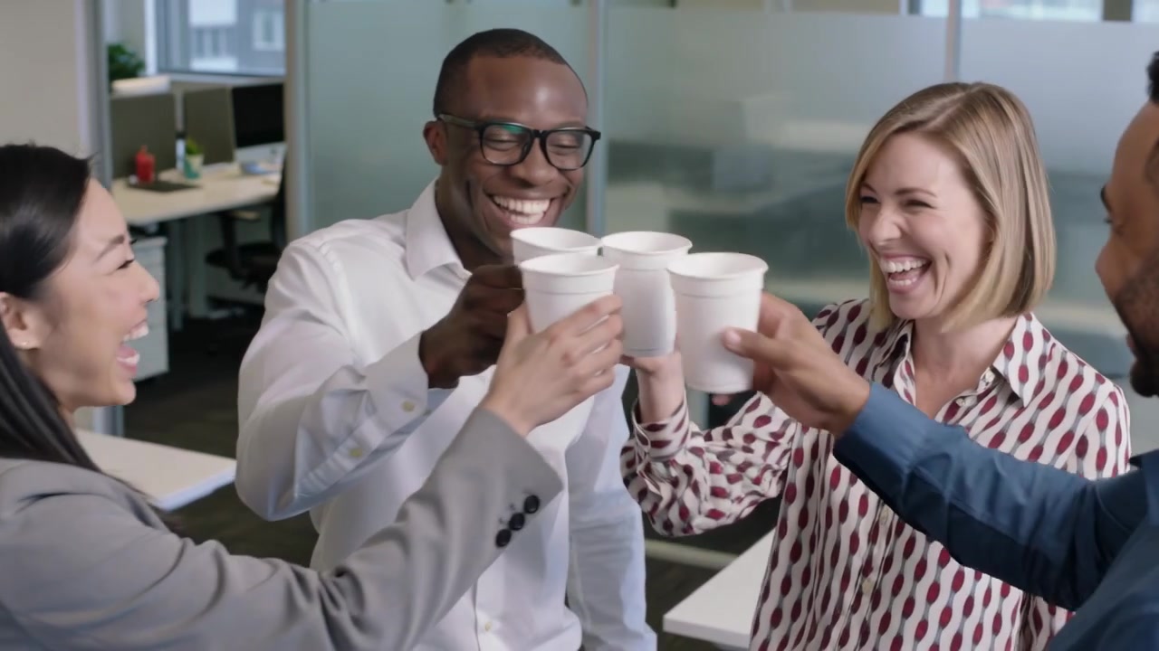 Equipo en la oficina con ropa de trabajo levantando tazas blancas, acercándose y chocándolas después de una reunión, celebrando