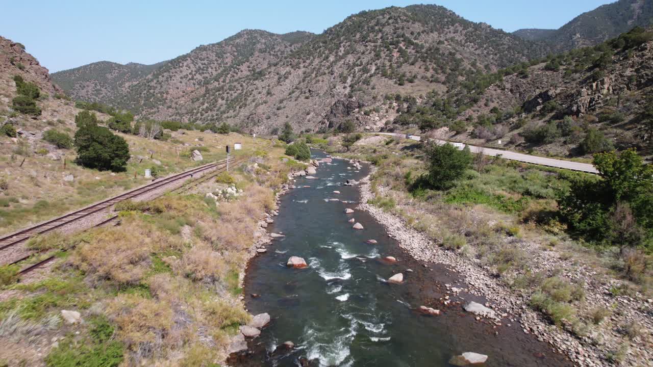 Aerial View of River Running Through Mountains with Train Tracks and Highway