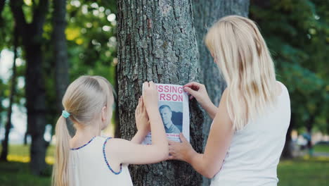 a woman with a child is attached to the tree flyer with information about the missing man