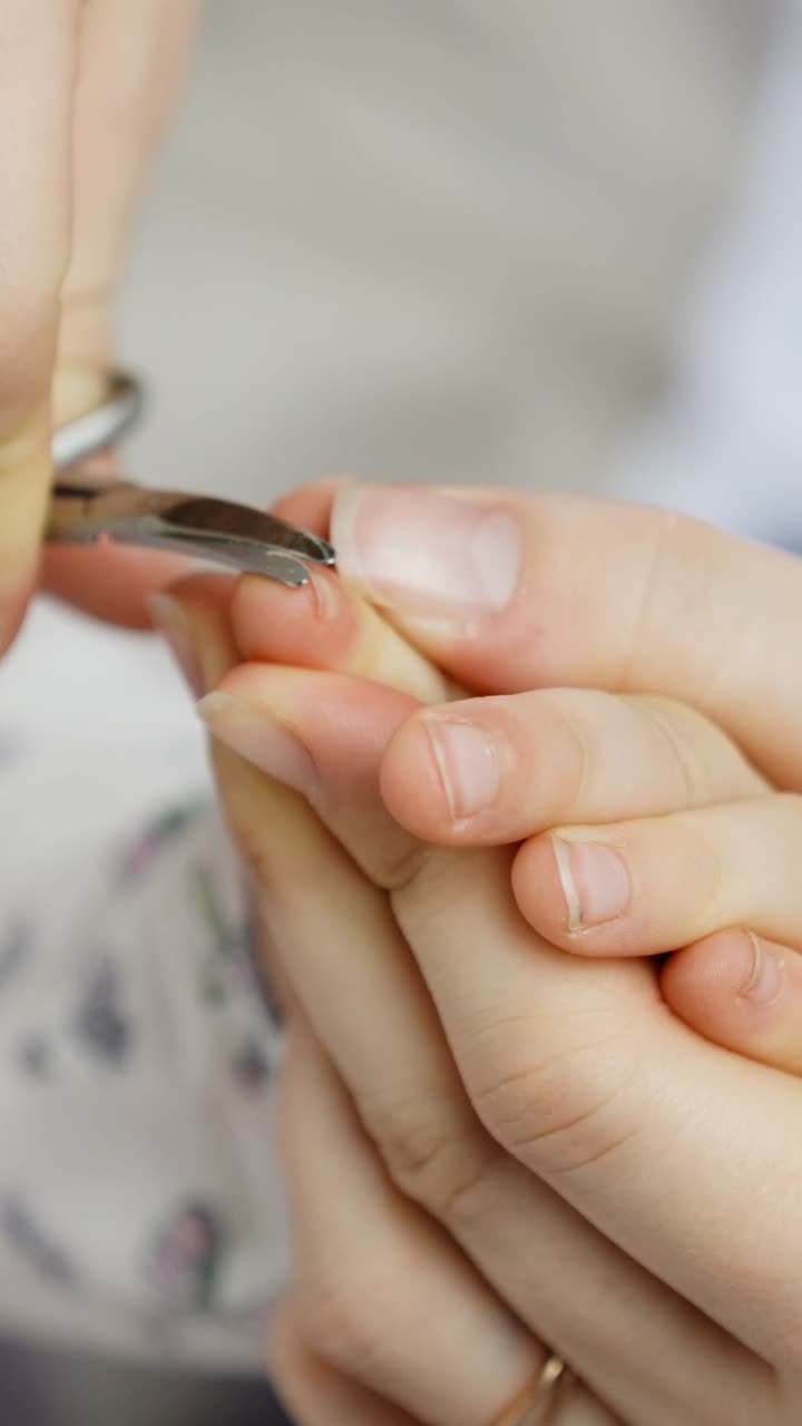 Adult Carefully Trimming Small Fingernails of a Toddler with Clippers