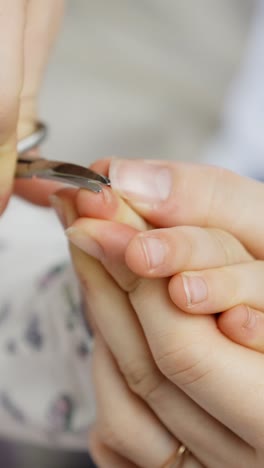 adult carefully trimming small fingernails of a toddler with clippers