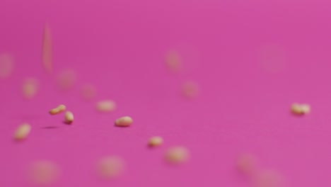 sesame seeds falling on pink background