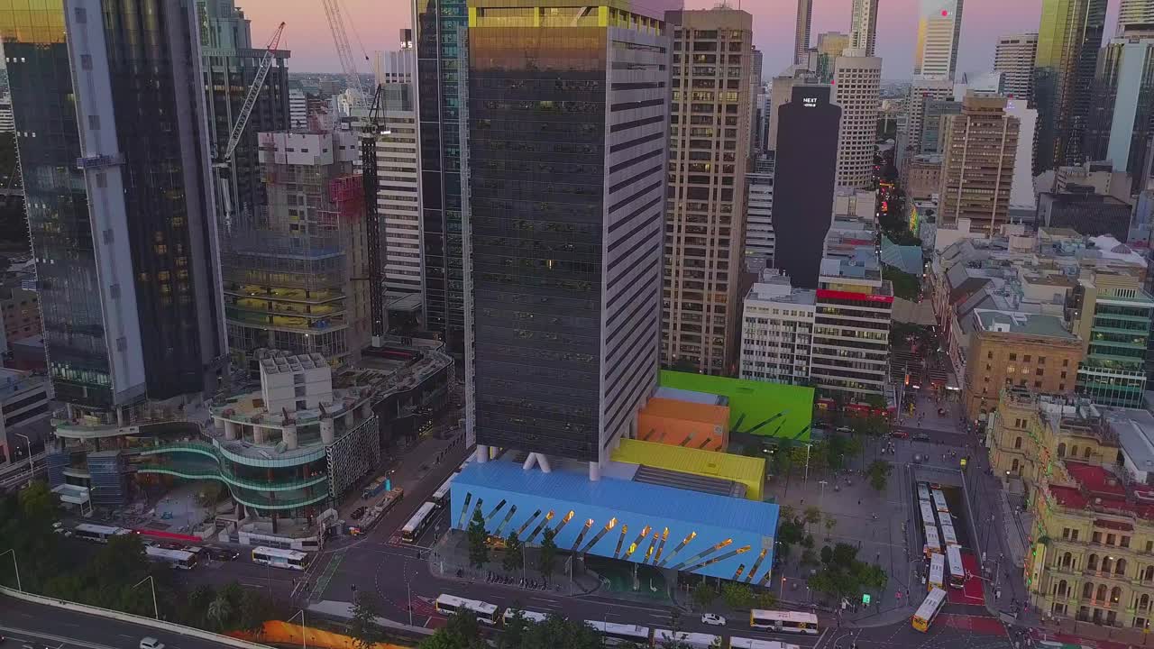 Vista aérea de uma cidade moderna e movimentada com arranha-céu em construção e rodovia ao pôr do sol