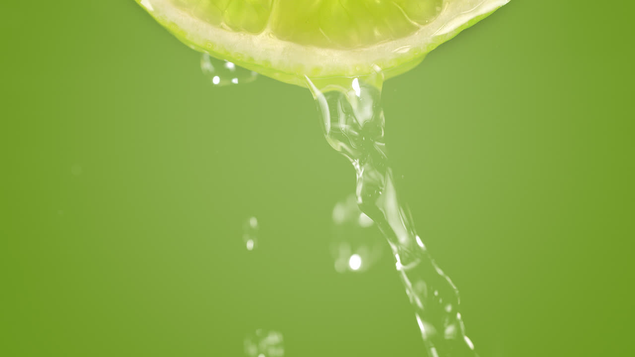 rodaja de cal salpicada con agua en cámara lenta y macro sobre un fondo verde