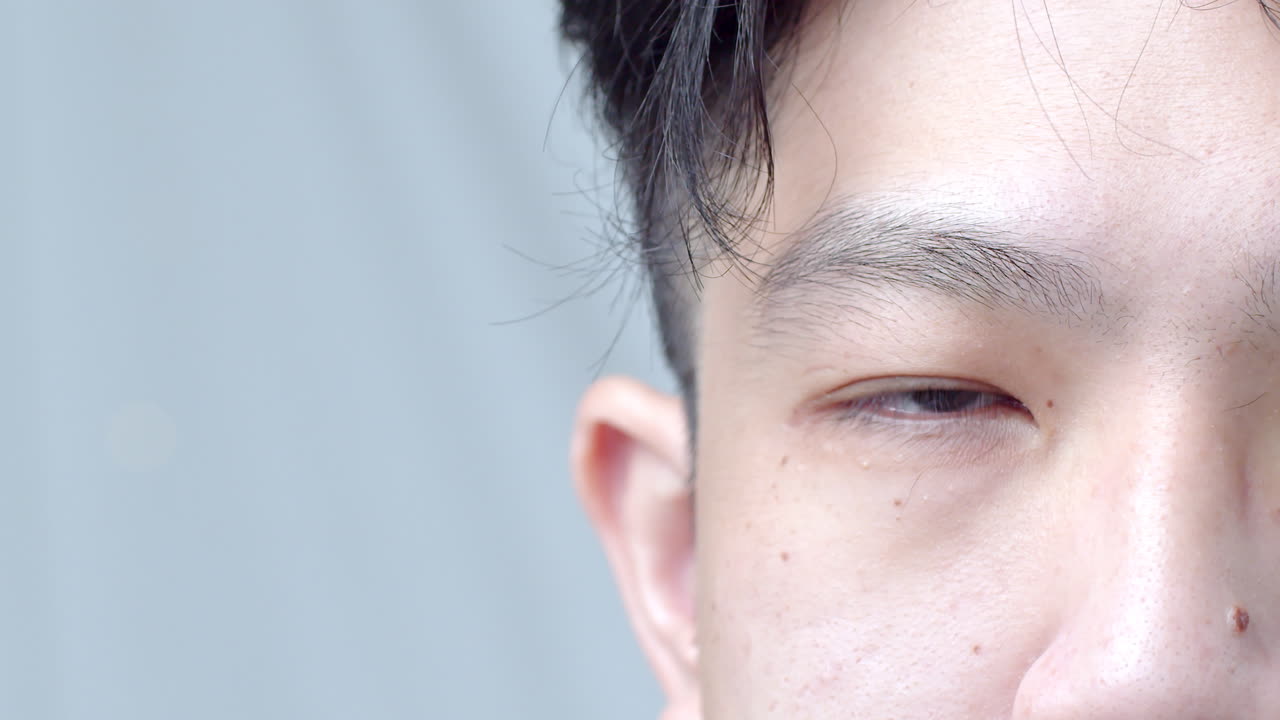 アジア人男性と健康な良い髪をクローズアップし、カメラを見て、髪を整えて自分を台無しにする