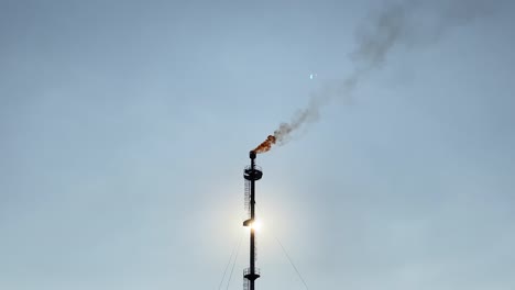 chimenea liberada por la industria de bengalas de gas en llamas, cielo despejado, alejar