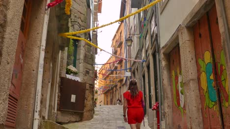 Beautiful-woman-in-red-walking-on-narrow-streets-in-old-town-in-Porto,-Portugal