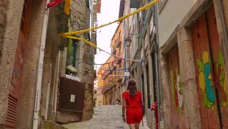 Schöne-Frau-In-Rot,-Die-Durch-Enge-Gassen-In-Der-Altstadt-Von-Porto,-Portugal,-Spaziert