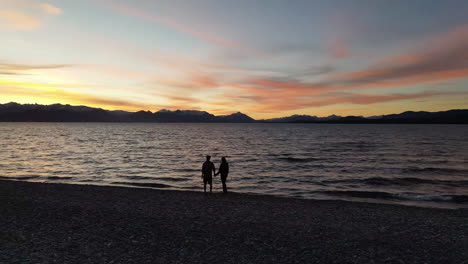 aerial - two people at sunset next to lake, rio negro, patagonia, argentina, circle pan