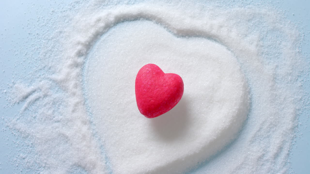 파란색 배경에 심장 모양의 설탕 위에 빨간 심장의 클로즈업, 느린 동작