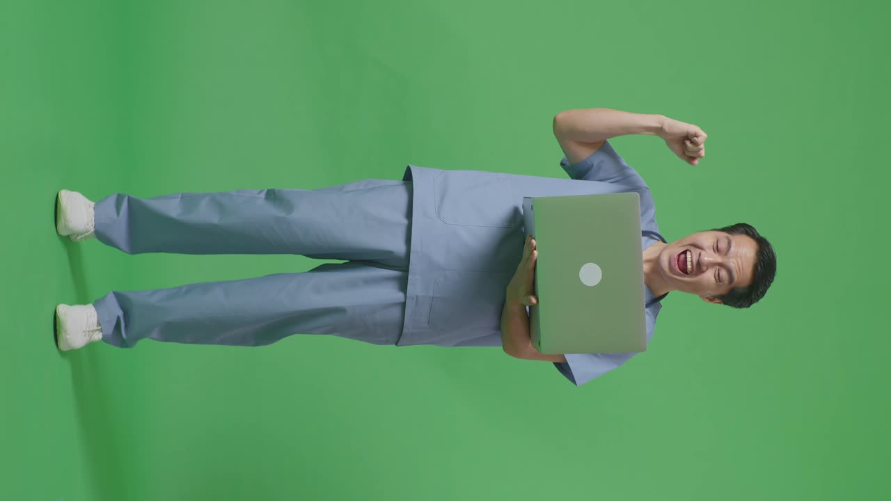 cuerpo lleno de médico masculino asiático con estetoscopio mirando una computadora portátil y celebrando el éxito en el fondo de la pantalla verde en el hospital