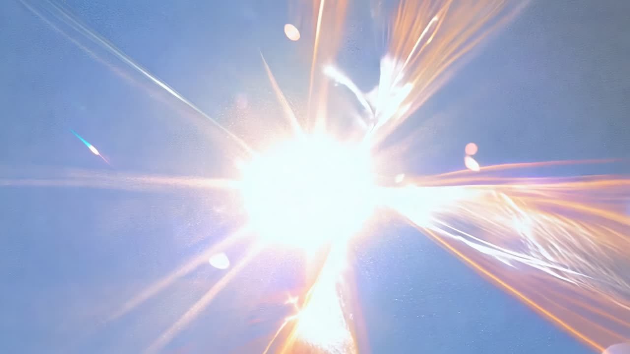 Abstract video still of a bright light burst with dynamic flares, captured from a low angle
