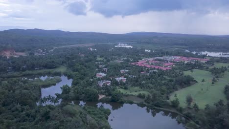 drone volando hacia el lalit golf and spa resort en raj baga, palolem, canacona, goa, india en un día nublado - toma aérea de drone