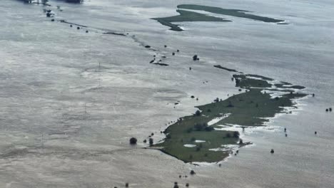 Aerial-orbiting-views-of-flooded-farm-fields-near-Gorinchem-Netherlands,-in-early-January-of-2024-with-a-light-snow-fall-in-the-foreground