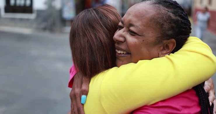 Due donne che si abbracciano e sorridono all'aperto