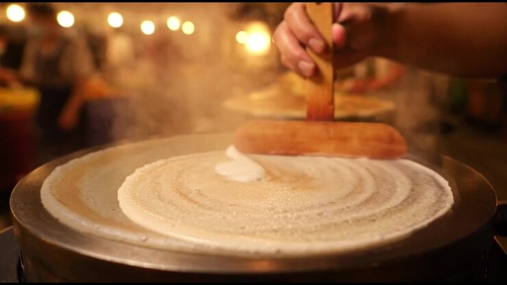 Street Food Vendor Spreading Crepe Batter on Hot Griddle