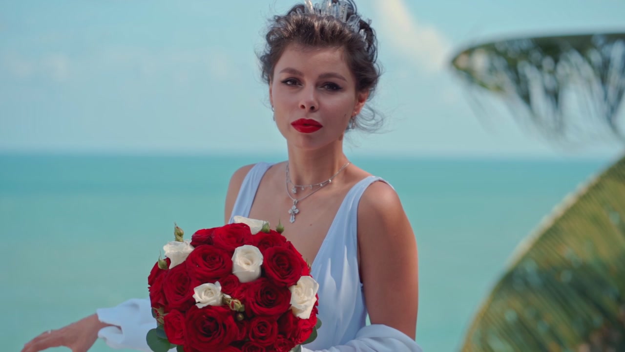 Bella Sposa che Regge un Bouquet di Rose Rosse in Riva al Mare