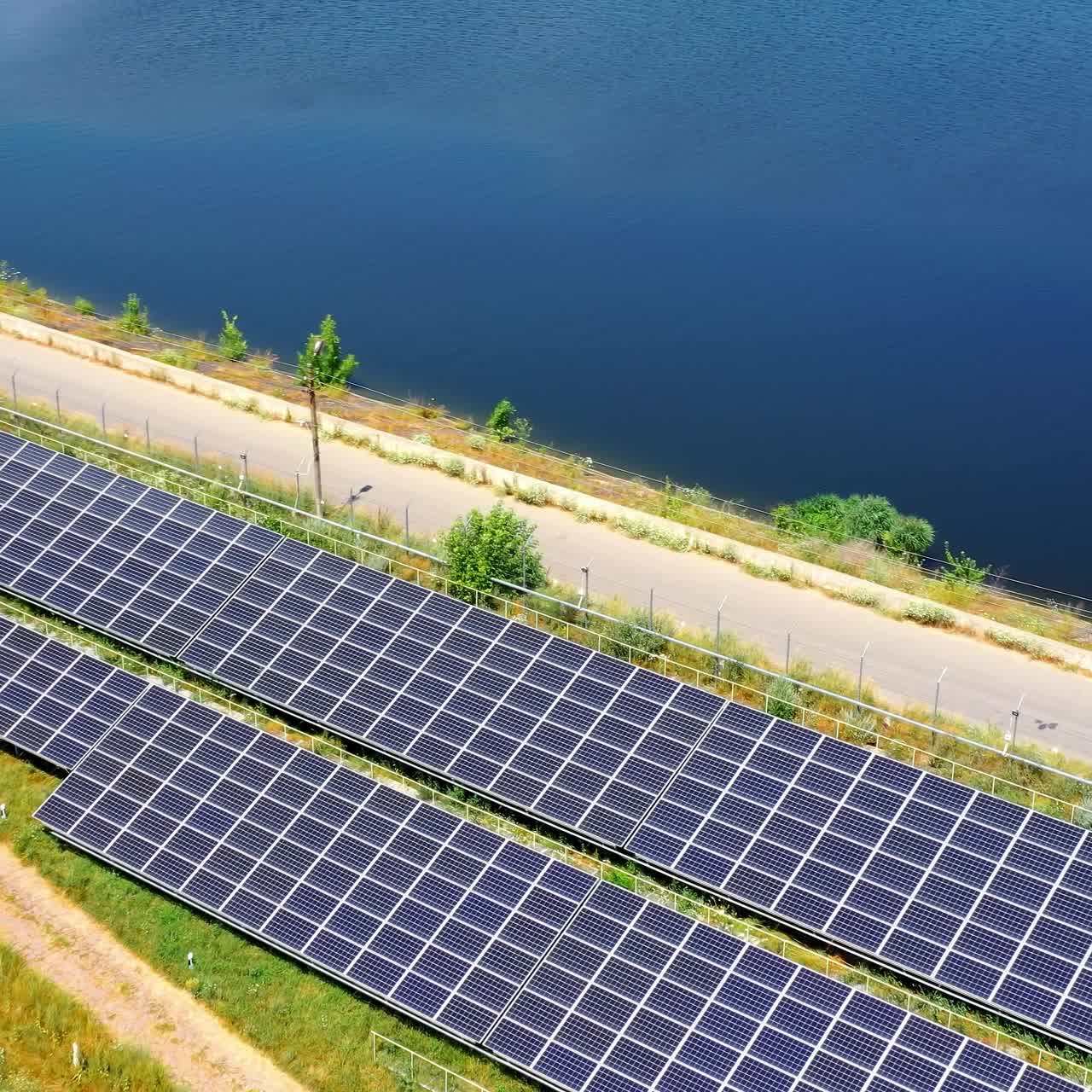 Photovoltaic panels on sea water background. Alternative clean energy from sun. Blue solar panels near the road. Production of clean energy