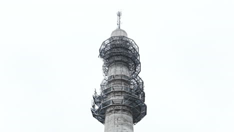 Toma-Aérea-Ascendente-En-ángulo-Bajo-De-Una-Sombría-Torre-De-Enlace-De-Radio-Y-Televisión-De-Hormigón-Industrial-En-Pasila,-Helsinki,-Finlandia-En-Un-Día-Brillante-Y-Brumoso