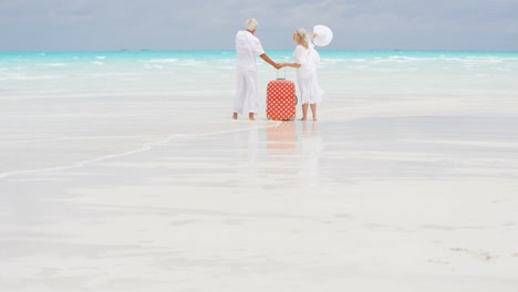 male female caucasian seniors on beach with suitcase