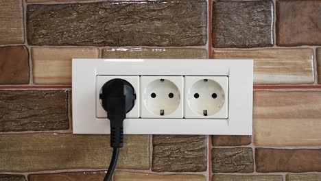 A-man's-hand-connecting-and-disconnecting-the-appliance-to-a-triple-power-wall-socket