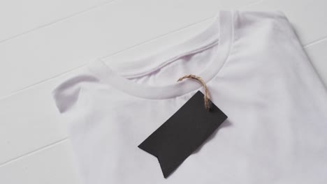 Video-of-flat-lay-of-white-t-shirt-with-tag-and-copy-space-on-white-background