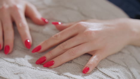close up guest hands with glossy red nails placed gently on body during calm therapy moment, resting on soft textured fabric in serene setting with natural lighting and peaceful atmosphere