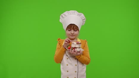 Child-girl-kid-dressed-as-professional-cook-chef-baker-eating-tasty-strawberry-cake-on-chroma-key