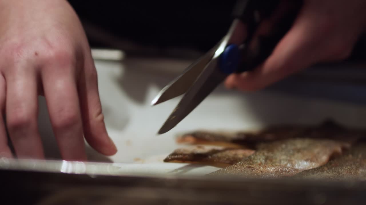 Chef is cutting crispy fish skins with scissors