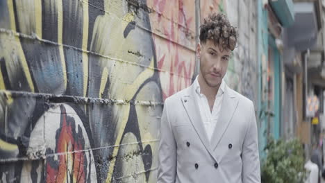 stylish man in gray suit by graffiti wall