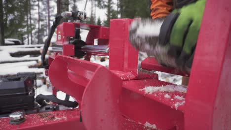 man is cutting frozen conifer woods using log splitter machine