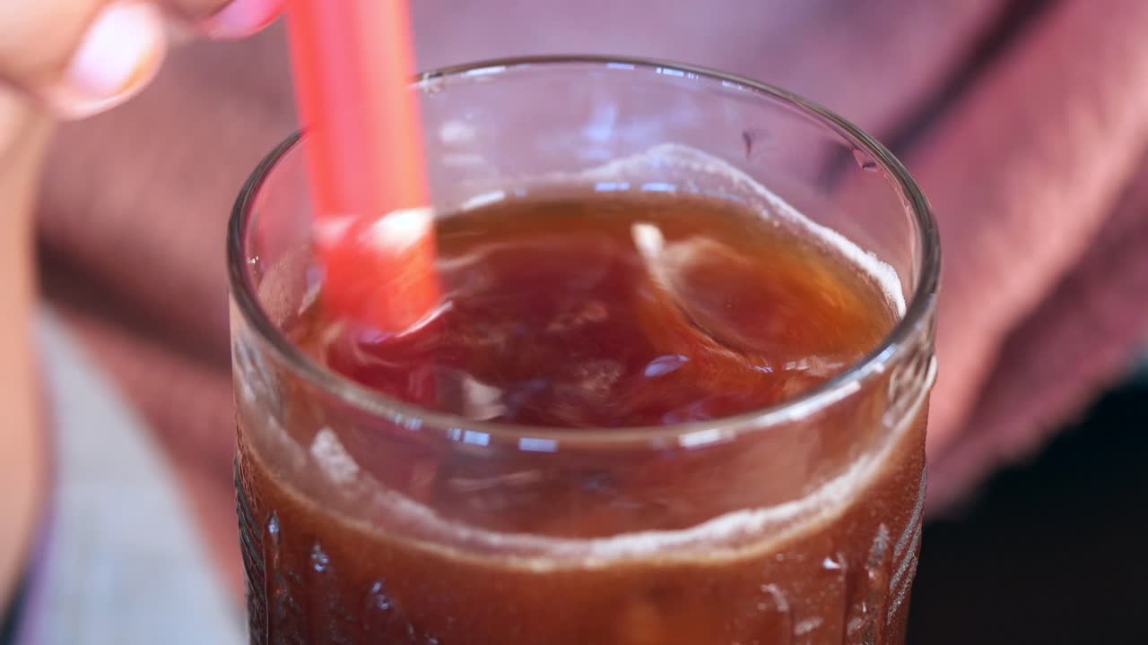 Una persona che gusta un caffè freddo con una cannuccia rossa