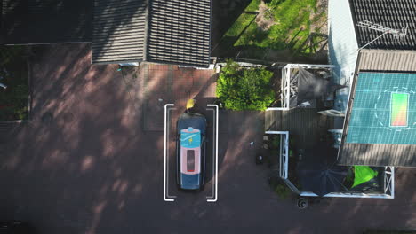 man charging a electric car on a house yard with electricity from solar panels