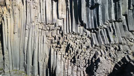 Aerial-drone-shot-flying-through-rocky-column-shaped-Studlagil-Canyon-with-the-Jokulsa-A-Bru-river-in-east-Iceland,-Europe-on-a-bright-sunny-day