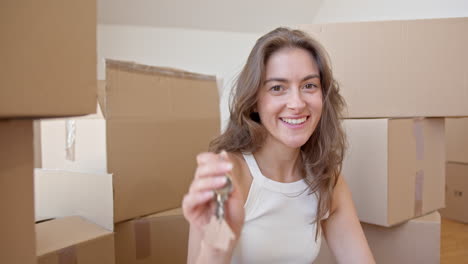 happy woman among stacked boxes showing keys to new house. rack focus