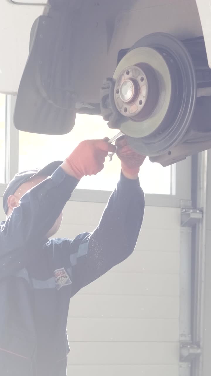 Meccanico che revisiona l'impianto frenante dell'auto in officina.