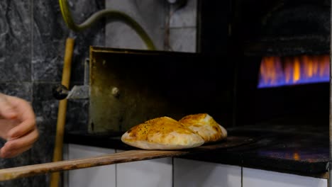 chef takes out new baked goods from oven