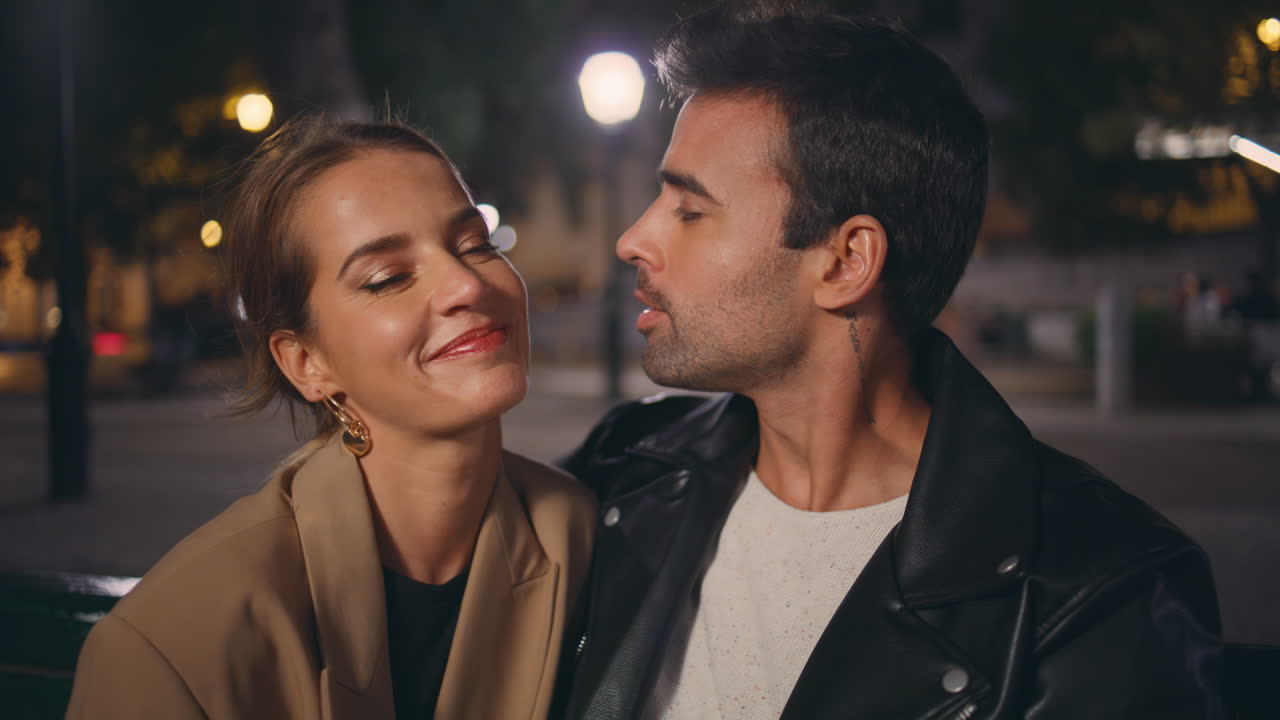 нежный парень целует девушку в щеку на свидании вблизи. улыбающиеся возлюбленные отдыхают в парке