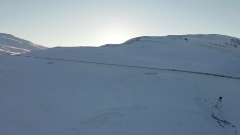 4K-drone-footage-of-car-driving-on-snowy-mountain-road-in-northern-Iceland-during-sunrise