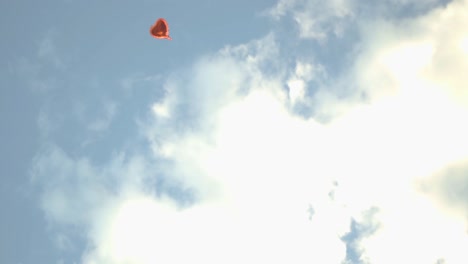 un globo rojo en forma de corazón flota solo en el cielo durante la puesta del sol